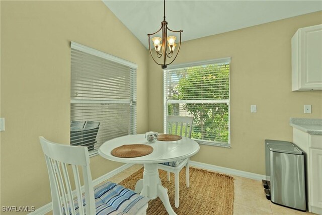 tiled dining room featuring an inviting chandelier and lofted ceiling