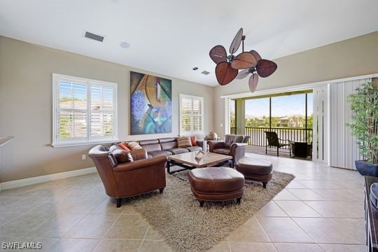 living area featuring baseboards, visible vents, a ceiling fan, and light tile patterned floors