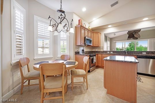 kitchen with hanging light fixtures, a chandelier, stainless steel appliances, a center island, and vaulted ceiling