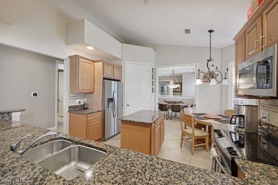 kitchen featuring a notable chandelier, a sink, stainless steel appliances, visible vents, and dark stone counters