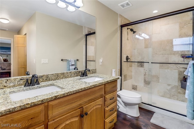 bathroom with wood-type flooring, vanity, a shower with shower door, and toilet