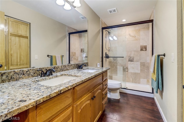 bathroom featuring hardwood / wood-style floors, vanity, toilet, and a shower with door