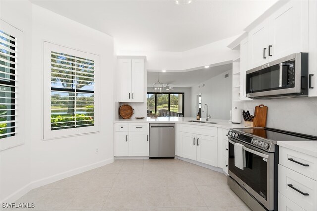 kitchen featuring sink, kitchen peninsula, appliances with stainless steel finishes, an inviting chandelier, and white cabinets