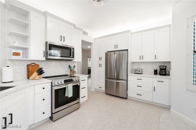 kitchen with stainless steel appliances, white cabinets, light tile patterned floors, and decorative backsplash