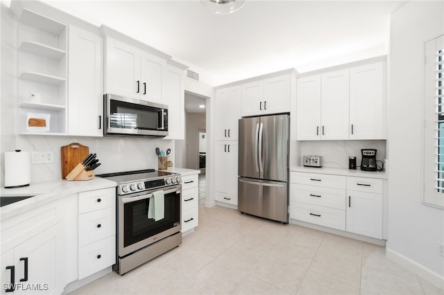 kitchen featuring appliances with stainless steel finishes, open shelves, light countertops, and decorative backsplash