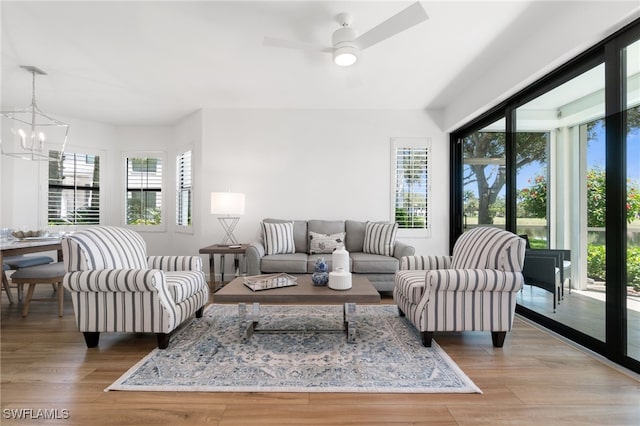 living area featuring a chandelier, light wood-type flooring, and ceiling fan