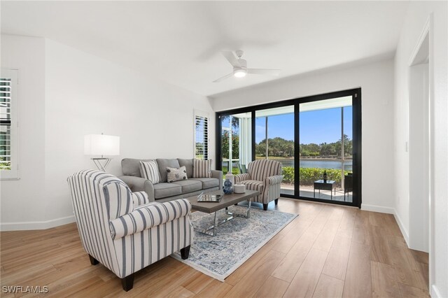 living room featuring light hardwood / wood-style floors, a water view, and ceiling fan