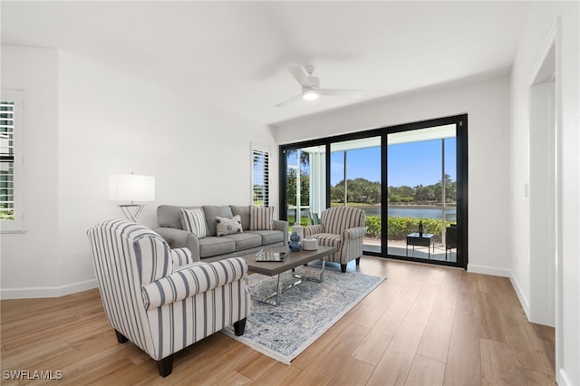 living room with light wood-type flooring, a water view, and ceiling fan