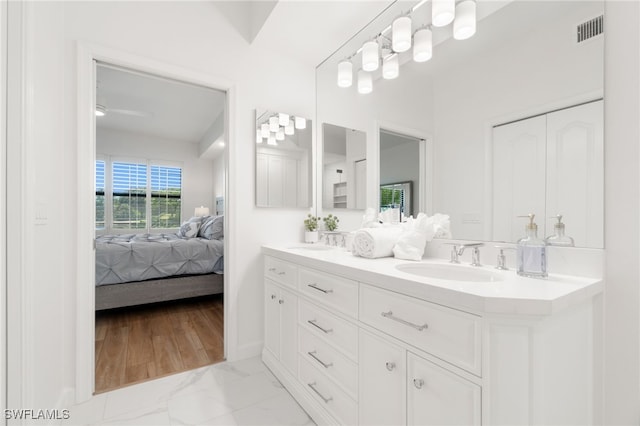full bath with ensuite bath, double vanity, and marble finish flooring