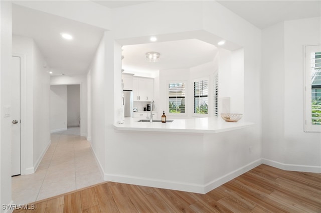 corridor featuring sink, a wealth of natural light, and light hardwood / wood-style flooring