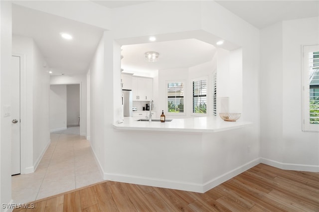 kitchen with freestanding refrigerator, light countertops, baseboards, light wood-type flooring, and recessed lighting