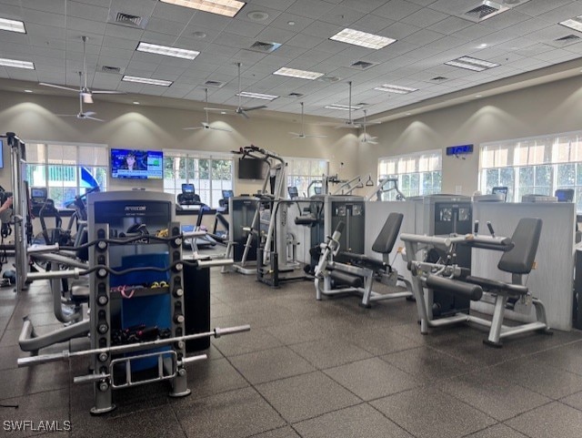 exercise room with a paneled ceiling, a high ceiling, and a healthy amount of sunlight