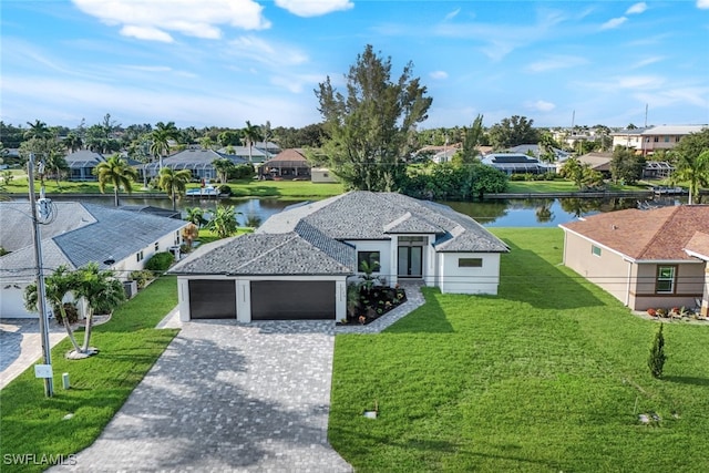 view of front of home featuring a garage, a residential view, a water view, decorative driveway, and a front yard