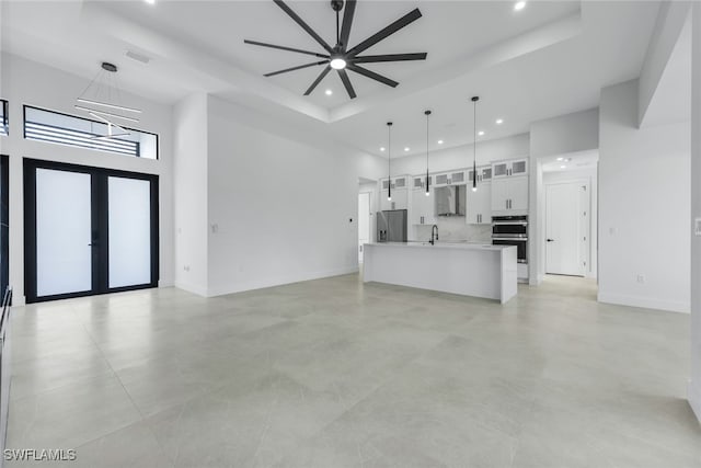 unfurnished living room with recessed lighting, a towering ceiling, visible vents, baseboards, and french doors