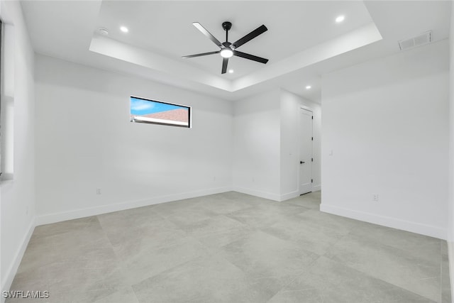 spare room featuring a ceiling fan, a raised ceiling, visible vents, and baseboards