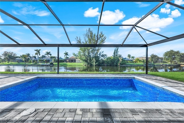 outdoor pool with glass enclosure, a patio, and a water view