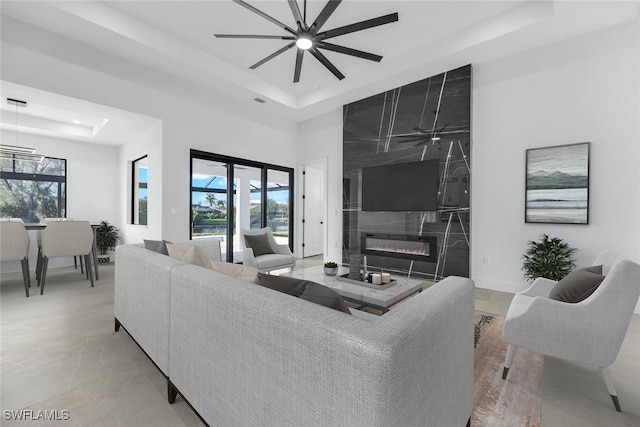 living room with a healthy amount of sunlight, a raised ceiling, and a high end fireplace