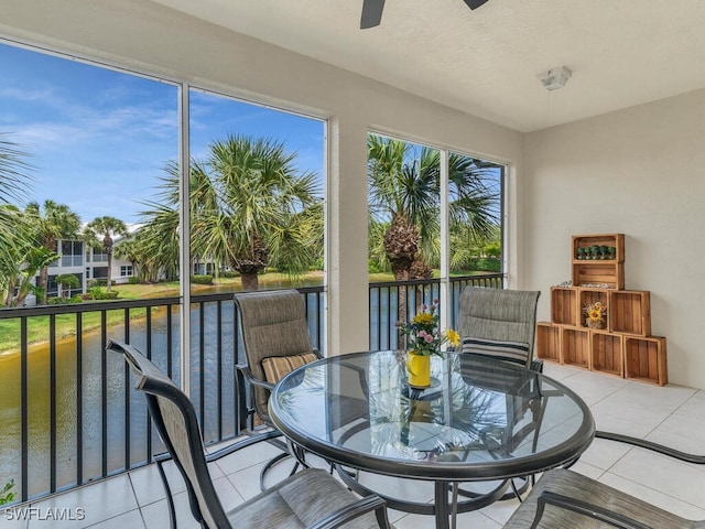 sunroom featuring ceiling fan and a water view