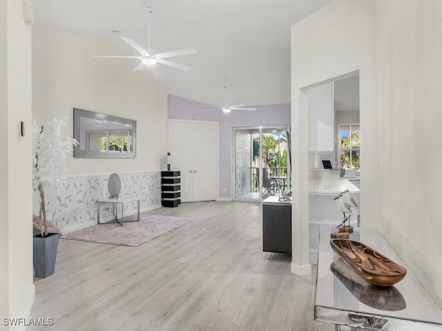 interior space featuring baseboards, ceiling fan, high vaulted ceiling, and wood finished floors