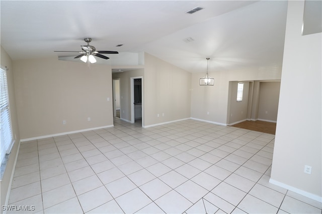 unfurnished room with ceiling fan with notable chandelier, light tile patterned flooring, and vaulted ceiling