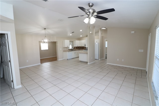 unfurnished living room featuring ceiling fan, light tile patterned floors, lofted ceiling, and sink