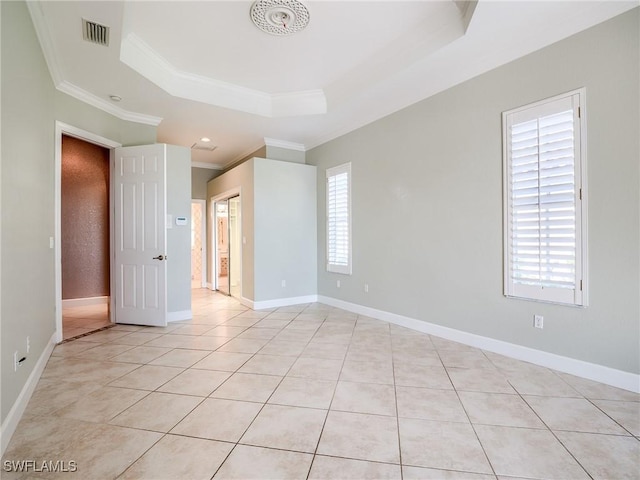 empty room with crown molding, plenty of natural light, a raised ceiling, and light tile patterned floors