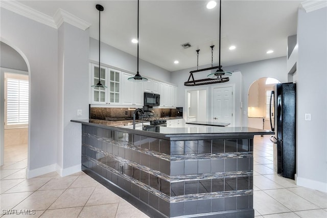 kitchen with hanging light fixtures, light tile patterned floors, kitchen peninsula, white cabinets, and black appliances