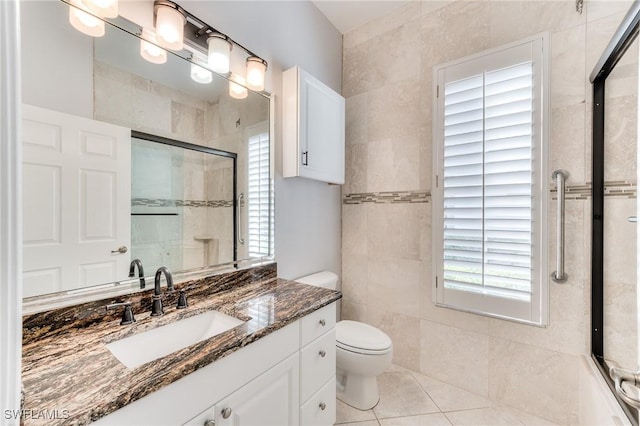 bathroom with tile walls, tile patterned flooring, vanity, toilet, and a shower with door