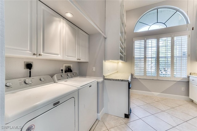 washroom with cabinets, plenty of natural light, washer and dryer, and light tile patterned floors