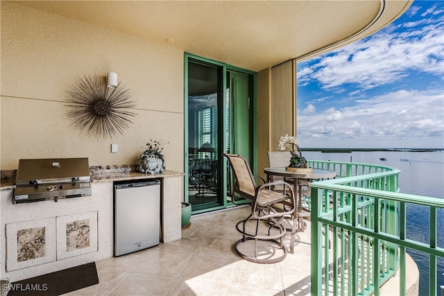 balcony featuring grilling area, a water view, and exterior kitchen