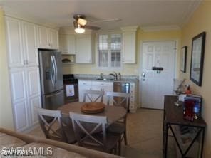 kitchen featuring black range oven, stainless steel fridge, white cabinets, crown molding, and ceiling fan