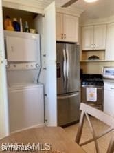 kitchen with range, stacked washer and dryer, stainless steel fridge with ice dispenser, and white cabinetry