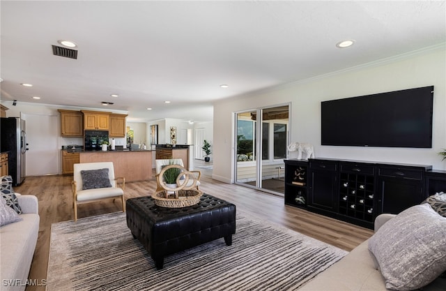 living room featuring light hardwood / wood-style flooring and crown molding