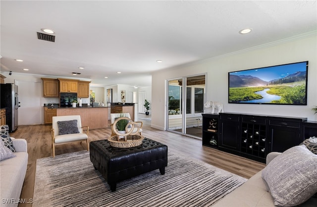 living room with crown molding and light hardwood / wood-style floors