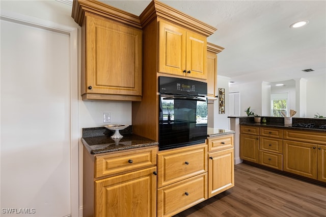 kitchen featuring black appliances, dark stone counters, and dark hardwood / wood-style flooring