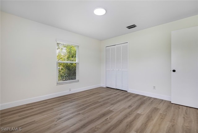 unfurnished bedroom with light hardwood / wood-style flooring and a closet