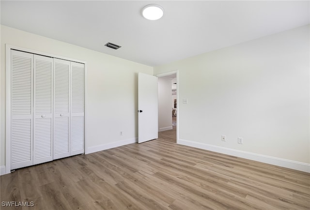 unfurnished bedroom with light wood-type flooring and a closet