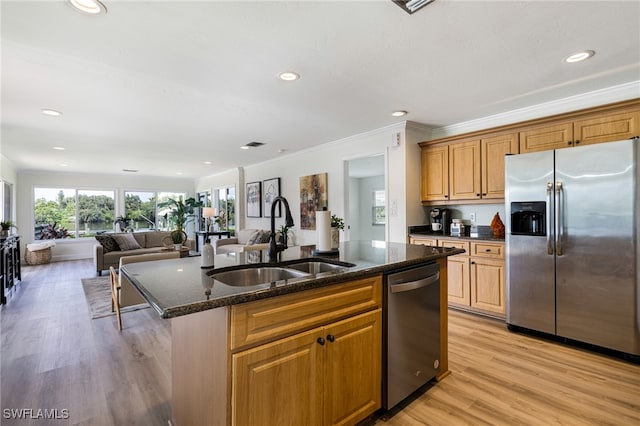 kitchen with stainless steel appliances, light wood-type flooring, a kitchen island with sink, and sink