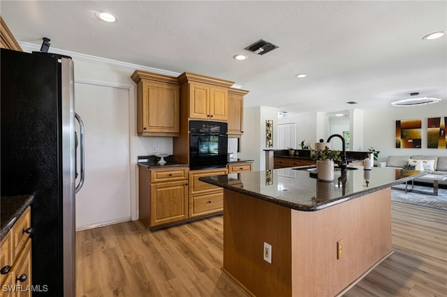 2110 Sebastian Ct, Alva, FL 33920 - kitchen featuring black oven, freestanding refrigerator, light wood-type flooring, a kitchen island with sink, and recessed lighting