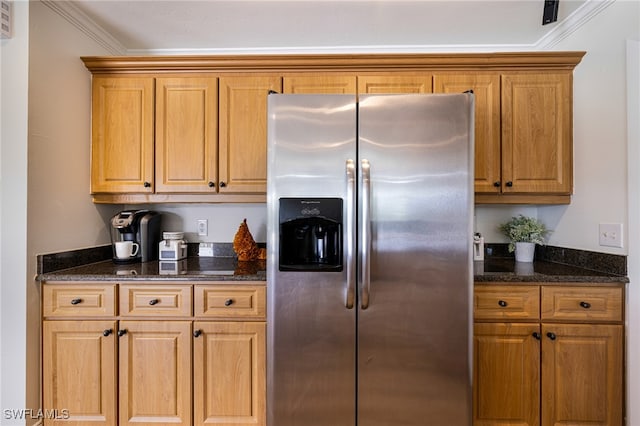 kitchen with dark stone countertops, stainless steel refrigerator with ice dispenser, and crown molding