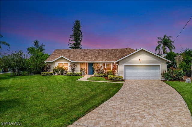 ranch-style house with a garage and a yard