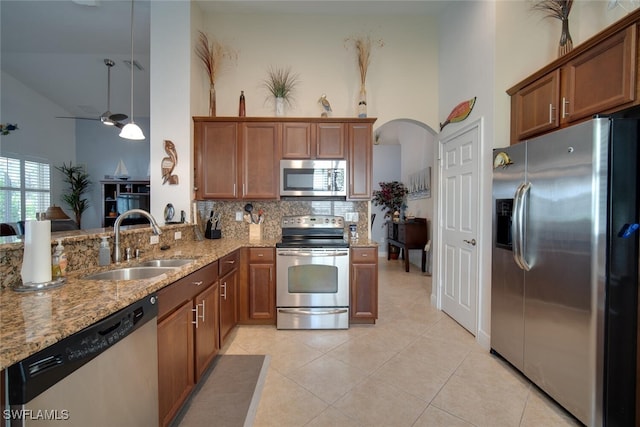 kitchen with light stone counters, light tile patterned flooring, sink, high vaulted ceiling, and appliances with stainless steel finishes