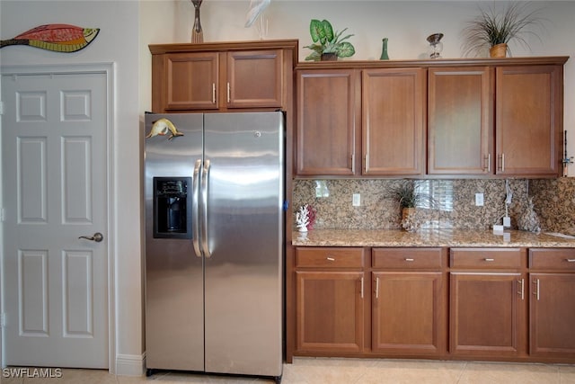 kitchen with light stone countertops, stainless steel fridge, light tile patterned floors, and decorative backsplash