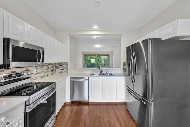 kitchen with appliances with stainless steel finishes, decorative backsplash, white cabinetry, dark wood-type flooring, and sink