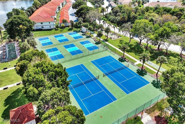 view of sport court with a lawn and a water view