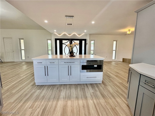 kitchen with light hardwood / wood-style floors, hanging light fixtures, oven, and a center island