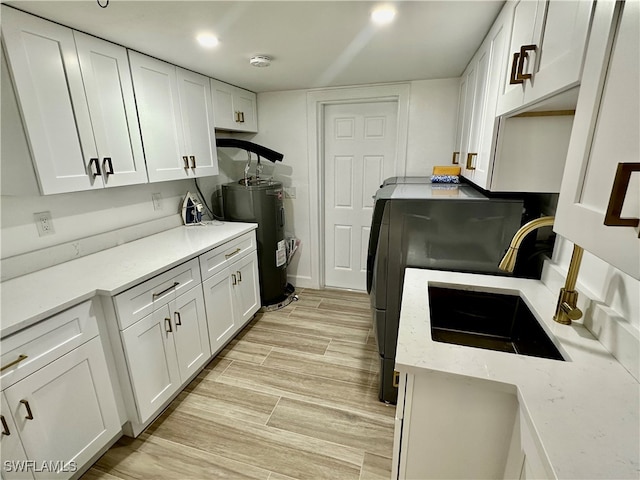 kitchen featuring sink, light hardwood / wood-style flooring, white cabinetry, water heater, and light stone countertops