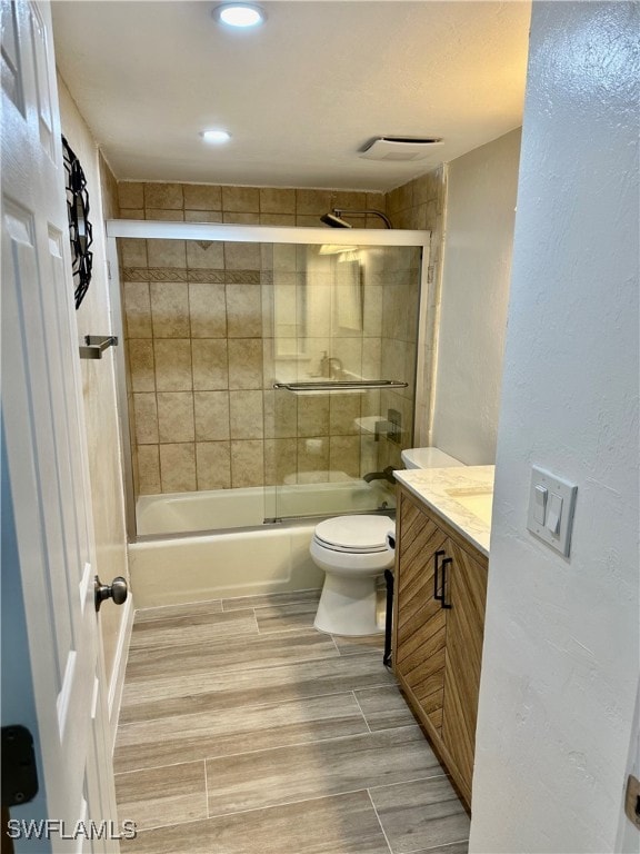 full bathroom featuring bath / shower combo with glass door, vanity, and toilet