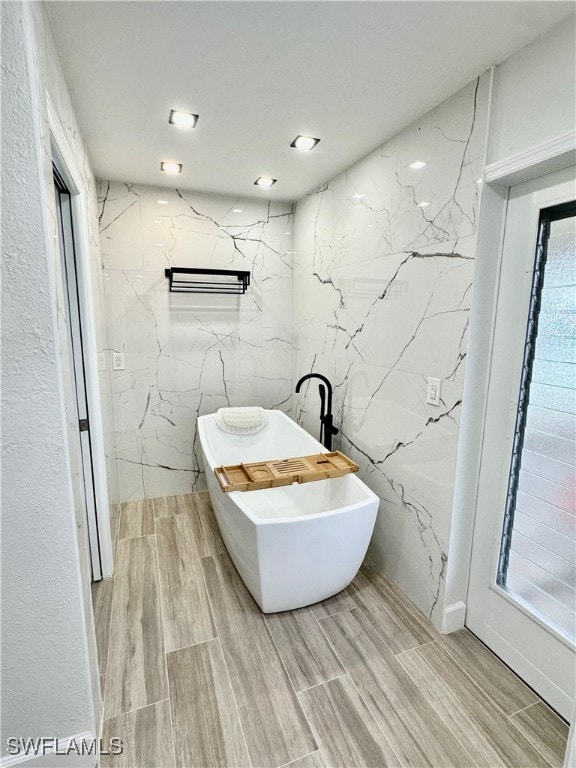 bathroom featuring a bathtub, tile walls, and hardwood / wood-style floors