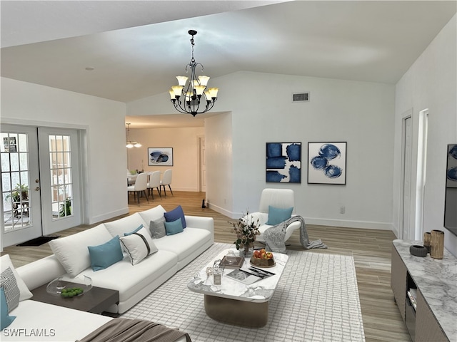 living room with lofted ceiling, light hardwood / wood-style flooring, french doors, and a chandelier